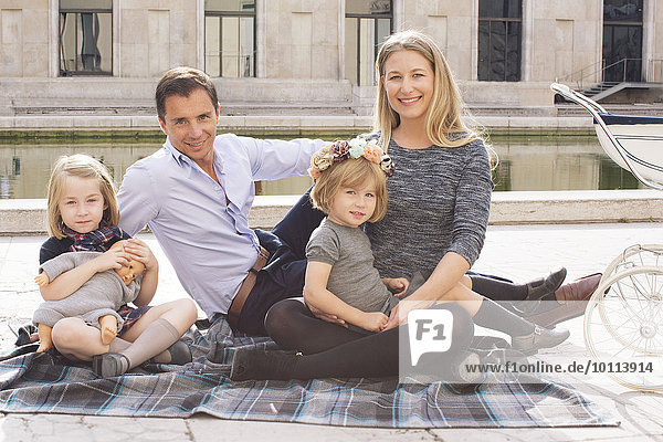 Familie auf Decke sitzend im Stadtpark  Portrait