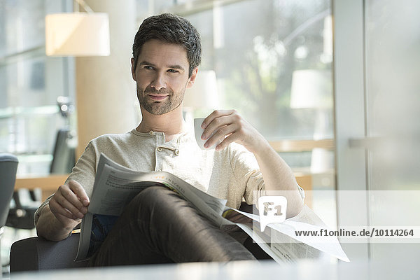 Mann entspannt mit Zeitung und Tasse Kaffee
