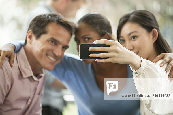 Frau fotografiert sich und ihre Freunde mit dem Smartphone