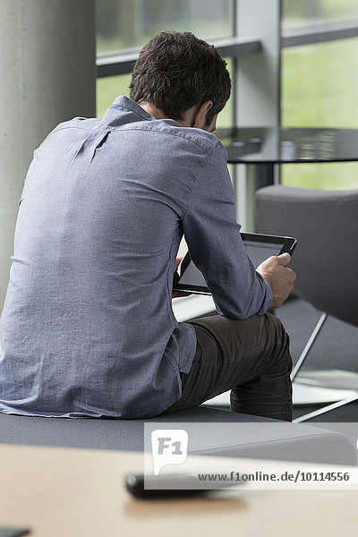 Mann mit digitalem Tablett allein zu Hause,  Rückansicht