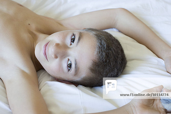 Boy lying on bed  smiling  portrait
