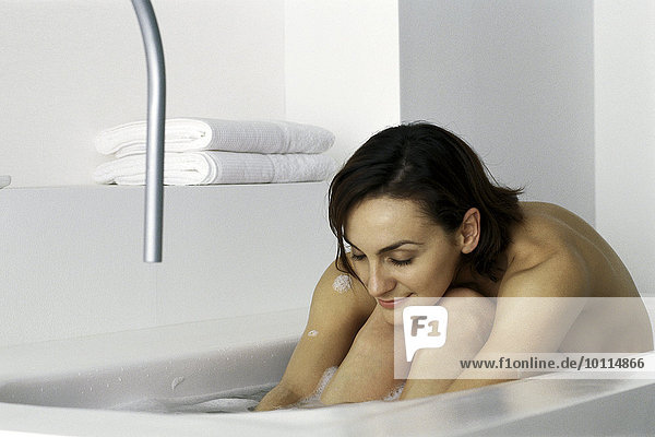 Frau im Bad sitzend mit Kopf auf Knien  Augen geschlossen