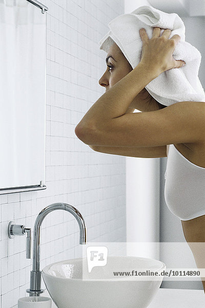 Frau vor dem Badezimmerspiegel,  Haartrocknung mit Handtuch
