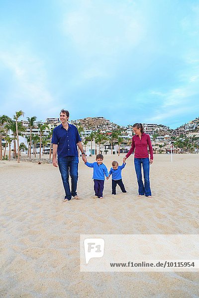 Young family  walking on beach  holding hands