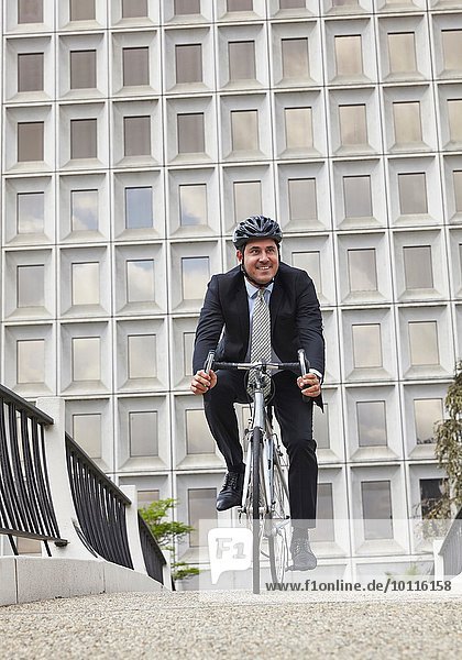 Vorderansicht eines Geschäftsmannes mit Fahrrad  Helm tragend  lächelnd