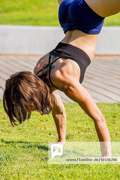 Junge Frau beim Handstand im Park