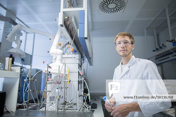 Porträt eines jungen Wissenschaftlers mit Probenflasche im Labor