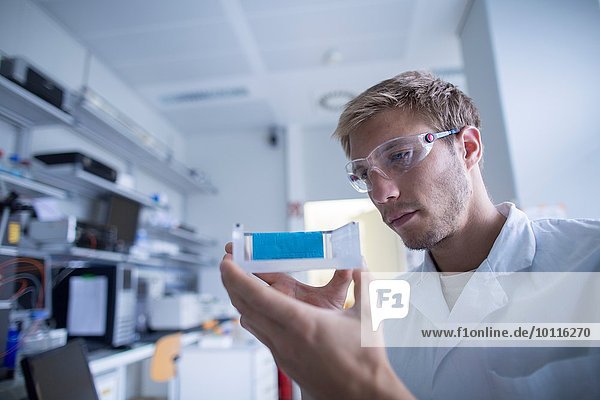 Junge männliche Wissenschaftlerin bereitet Experiment im Labor vor