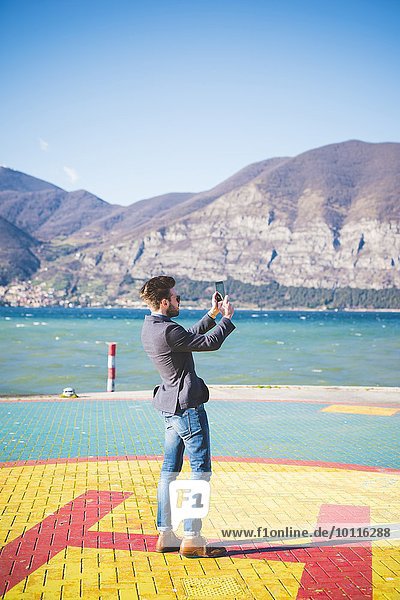 Junger Mann macht Smartphone-Fotos vom Hubschrauberlandeplatz  Rovato  Brescia  Italien