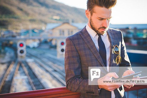 Junger Mann mit digitalem Tablett auf der Eisenbahnbrücke