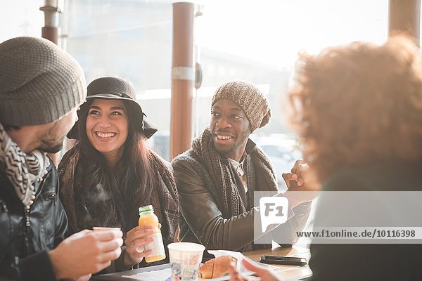 Vier junge erwachsene Freunde beim Plaudern im Straßencafé