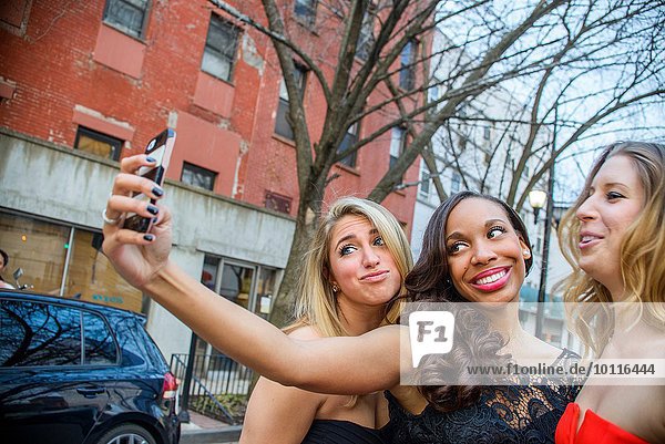 Drei glamouröse junge erwachsene Freundinnen nehmen Smartphone Selfie auf die Straße
