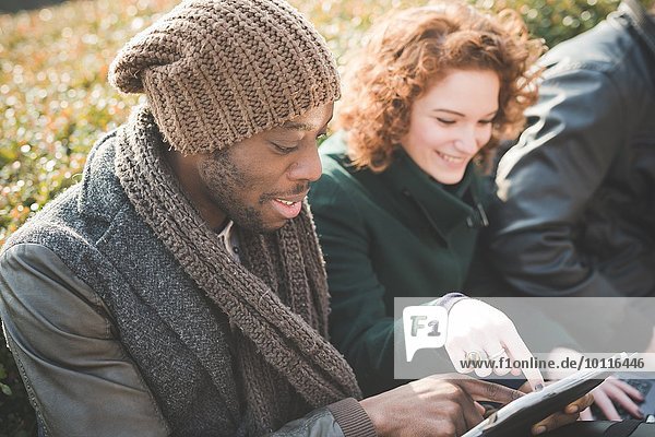 Junger Mann und Frau mit Touchscreen auf digitalem Tablett im Park