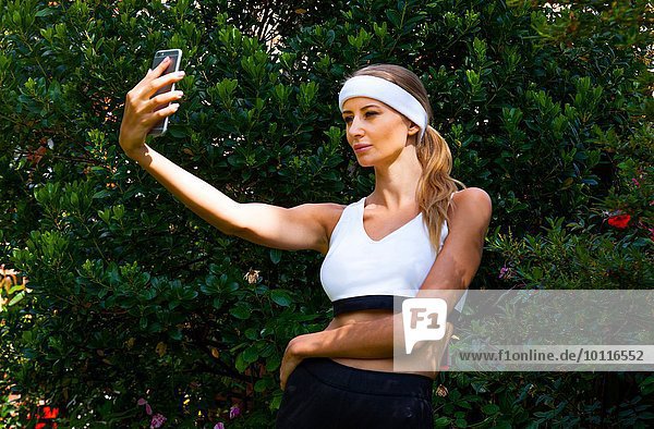 Woman wearing sports top taking selfie in garden