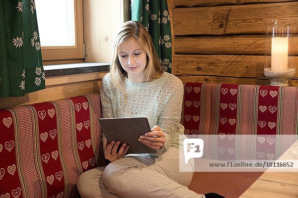 Junge Frau liest digitales Tablett im Blockhaus