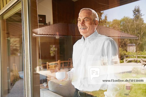 Senior Mann zu Hause  Kaffee trinken  aus dem Fenster schauen