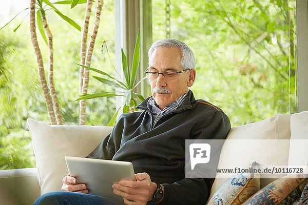 Senior Mann zu Hause  mit digitalem Tablett