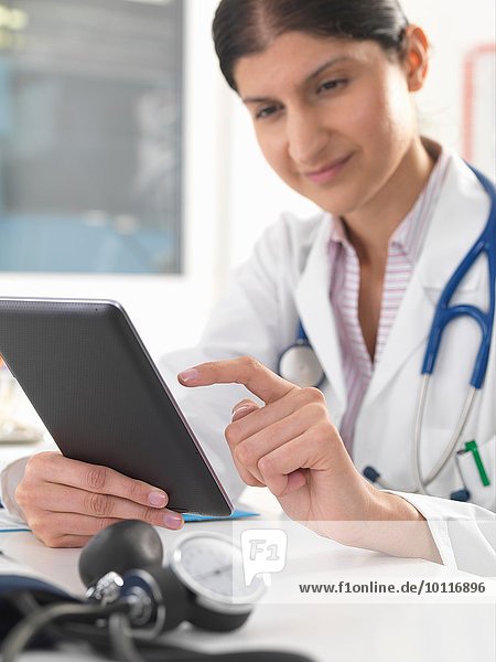 Female doctor updating medical records using digital tablet