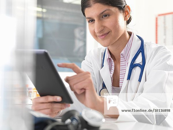 Female doctor using digital tablet touchscreen to update medical records