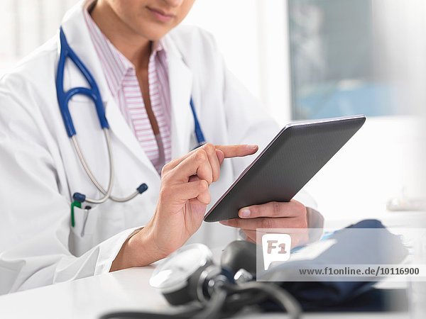 Ausschnittaufnahme einer Ärztin mit digitalem Tablett-Touchscreen zur Aktualisierung von Krankenakten