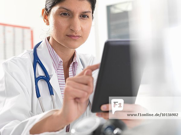 Female doctor using digital tablet touchscreen for medical records