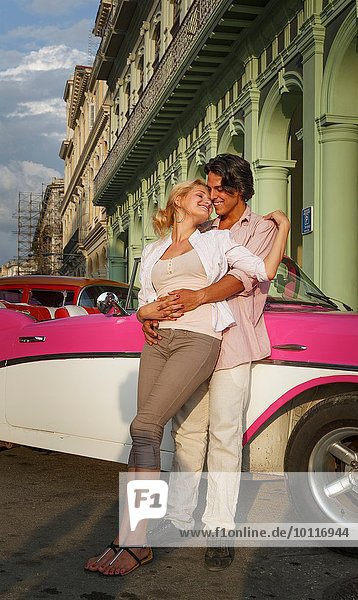 Junges Paar lehnt sich an Vintage Cabriolet  Havanna  Kuba