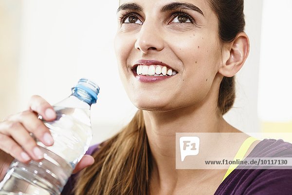 Nahaufnahme eines Porträts einer jungen Frau  die eine Bewegungspause einlegt  um Trinkwasser zu trinken.