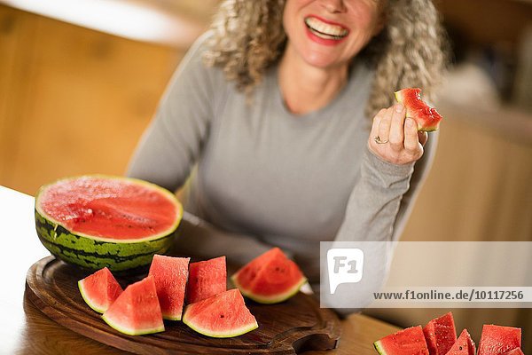 Reife Frau isst Wassermelone in der Küche