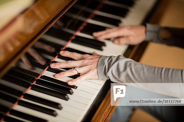 Hände einer reifen Frau beim Klavierspielen