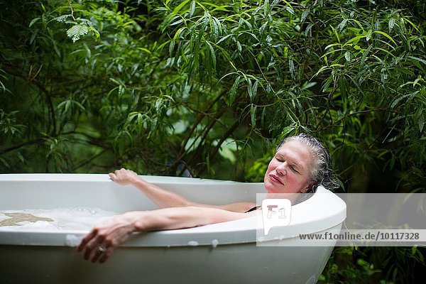 Reife Frau entspannt sich im Garten-Sprudelbad im Öko-Retreat