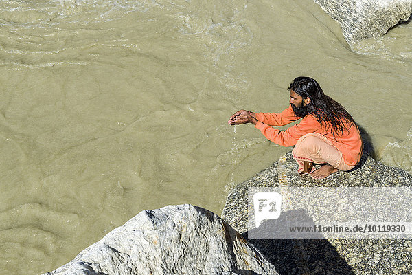 Ein Sadhu  heiliger Mann  sitzend und betend auf einem Felsen am Gaumukh  Hauptquelle des Ganges  Gangotri  Uttarakhand  Indien  Asien