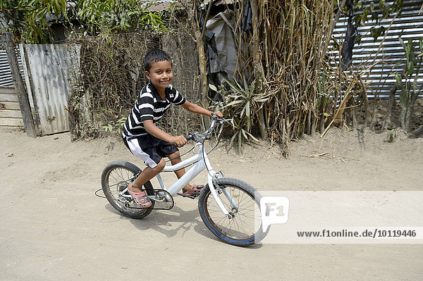 Boy riding his bike from a peace initiative by the police and the Catholic Church in the slum of Colonia Monsenor Romero  Distrito Itália  San Salvador  El Salvador  North America