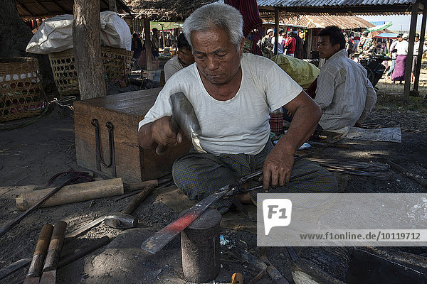 Einheimischer Mann  Schmied  schmiedet eine Machete  auf dem Land-Markt in Maing Thauk  Inle-See  Shan-Staat  Myanmar  Asien