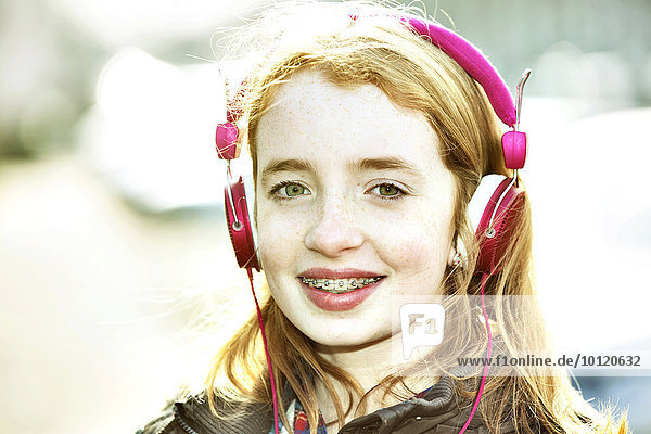Mädchen  rothaarig  mit Smartphone und Kopfhörer in der Stadt