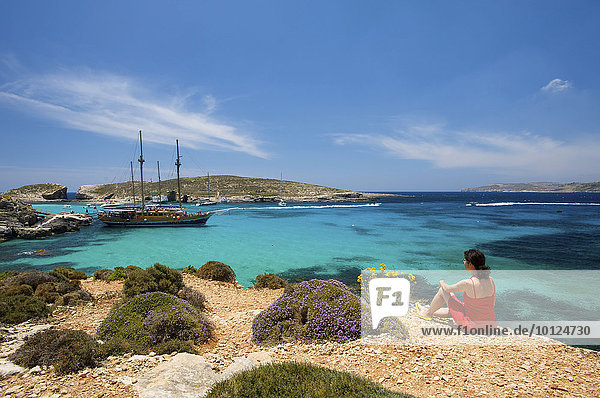 Frau blickt auf Ausflugsschiffe in der Blauen Lagune von Comino  Malta  Europa