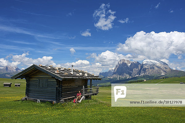 Woman sitting at an alpine hut in front of Piatto Mountain and Sasso Lungo Mountains  Seiser Alm  Dolomiten  South Tyrol province  Trentino-Alto Adige  Italy  Europe