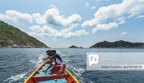 Einheimischer Mann sitzt am Heck und steuert ein Longtail-Boot im türkisen Meer  Insel Koh Tao  Golf von Thailand  Thailand  Asien