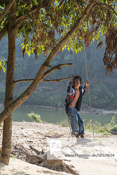 Kleiner Junge  Volksstamm Orang Asil  Ureinwohner schaukelt und schaut in die Ferne  Nationalpark Taman Negara  Malaysia  Asien