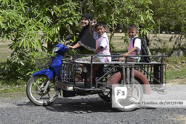 Frau mit Kopftuch und Schulkindern auf einem Motorroller  Koh Samui  Thailand  Asien