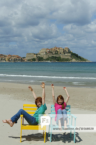 Kinder sitzen in bunten Strandstühlen am Strand von Calvi  Département Haute-Corse  Korsika  Frankreich  Europa