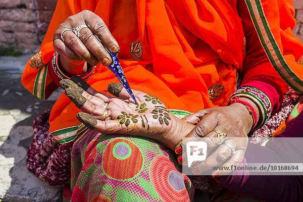 Eine indische Frau bemalt eine Hand mit Henna vor dem Badrinath-Tempel Char Dham Pilgerort Badrinath Uttarakhand Indien Asien