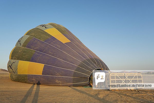 Pilot beim Befüllen eines Heißluftballons mit zwei Brennern  Startvorbereitung bei Sonnenaufgang  Namib-Wüste  NamibRand-Naturreservat  Namibia  Afrika