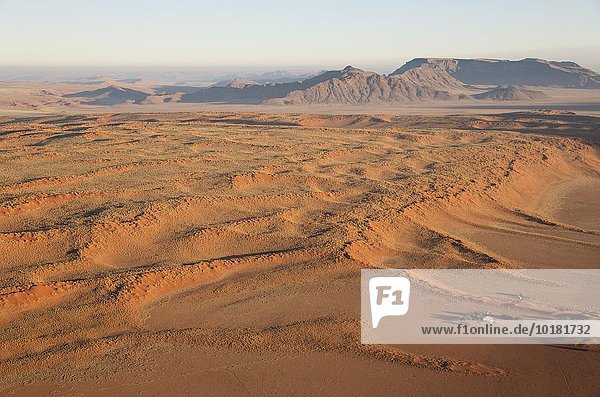 Luftbild aus einem Heißluftballon  Bauernhaus am Fuße einer großen grasbewachsenen Düne am Rande der Namib-Wüste  NamibRand-Naturreservat  Namibia  Afrika