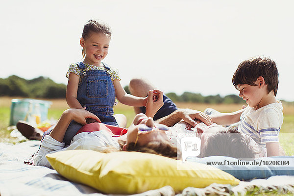 Familie entspannt auf der Decke im sonnigen Feld