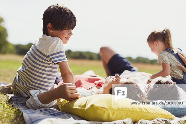 Familie entspannt auf der Decke im sonnigen Feld