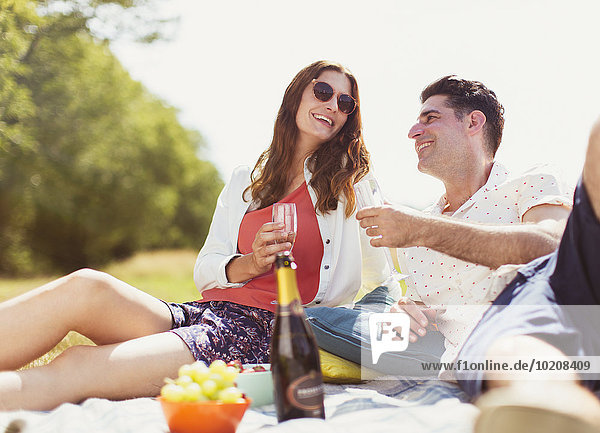 Pärchen trinkt Champagner auf Picknickdecke im sonnigen Feld