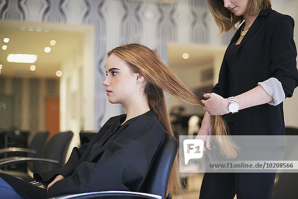 Friseur bereitet sich darauf vor,  die langen Haare des Kunden im Salon zu schneiden.