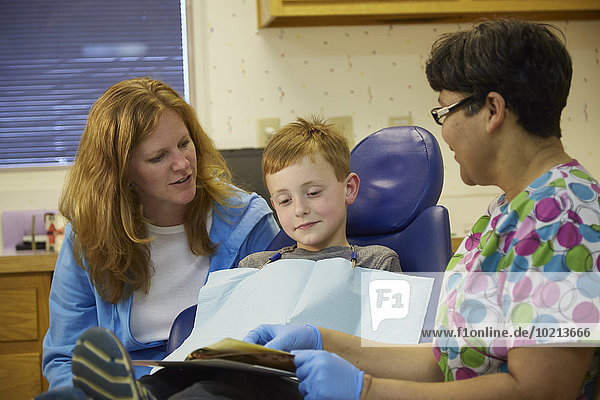 Pediatric dentist talking to patient and mother
