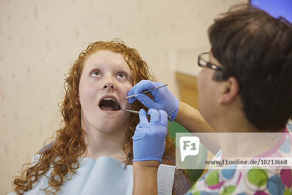 Pediatric dentist examining teeth of teenage patient