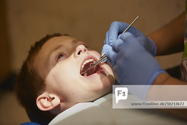 Pediatric dentist examining teeth of patient